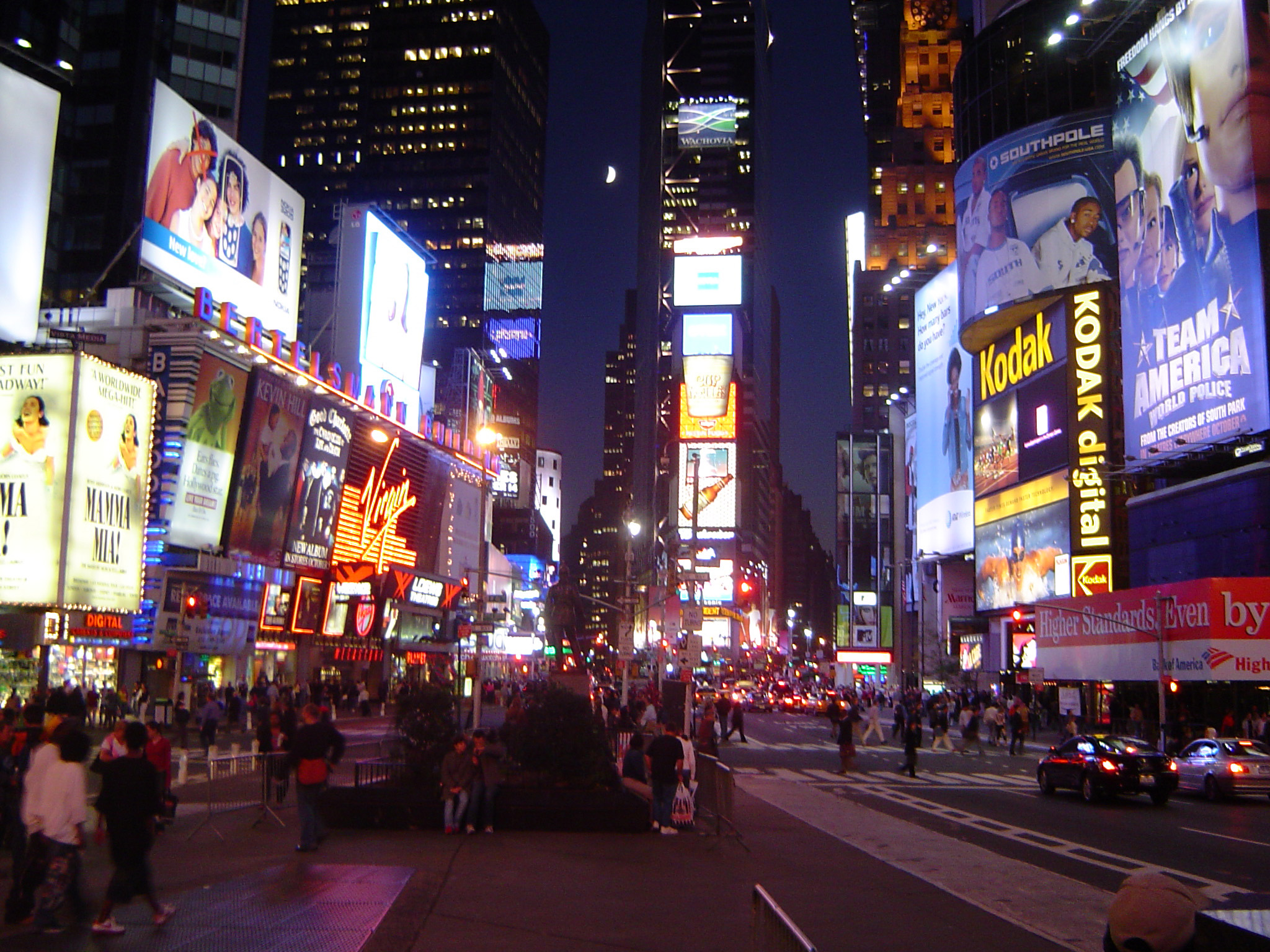 an image of Busy night street scene in Times Square, New York with brightly colored neon signs and pedestrians and shoppers