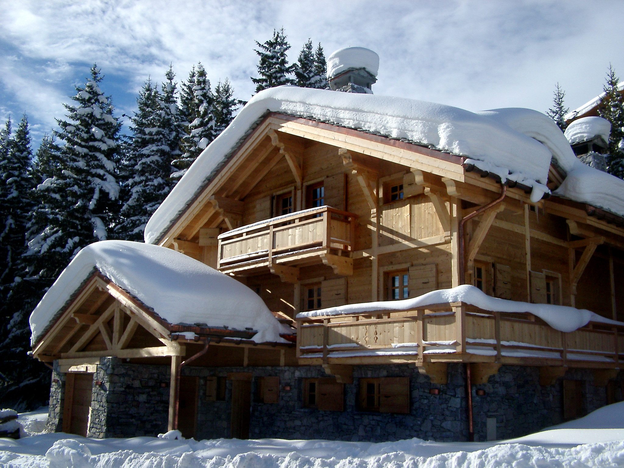 an image of Scenic view of a traditional wooden snow covered alpine lodge set amongst evergreen fir trees in a steep mountain valley