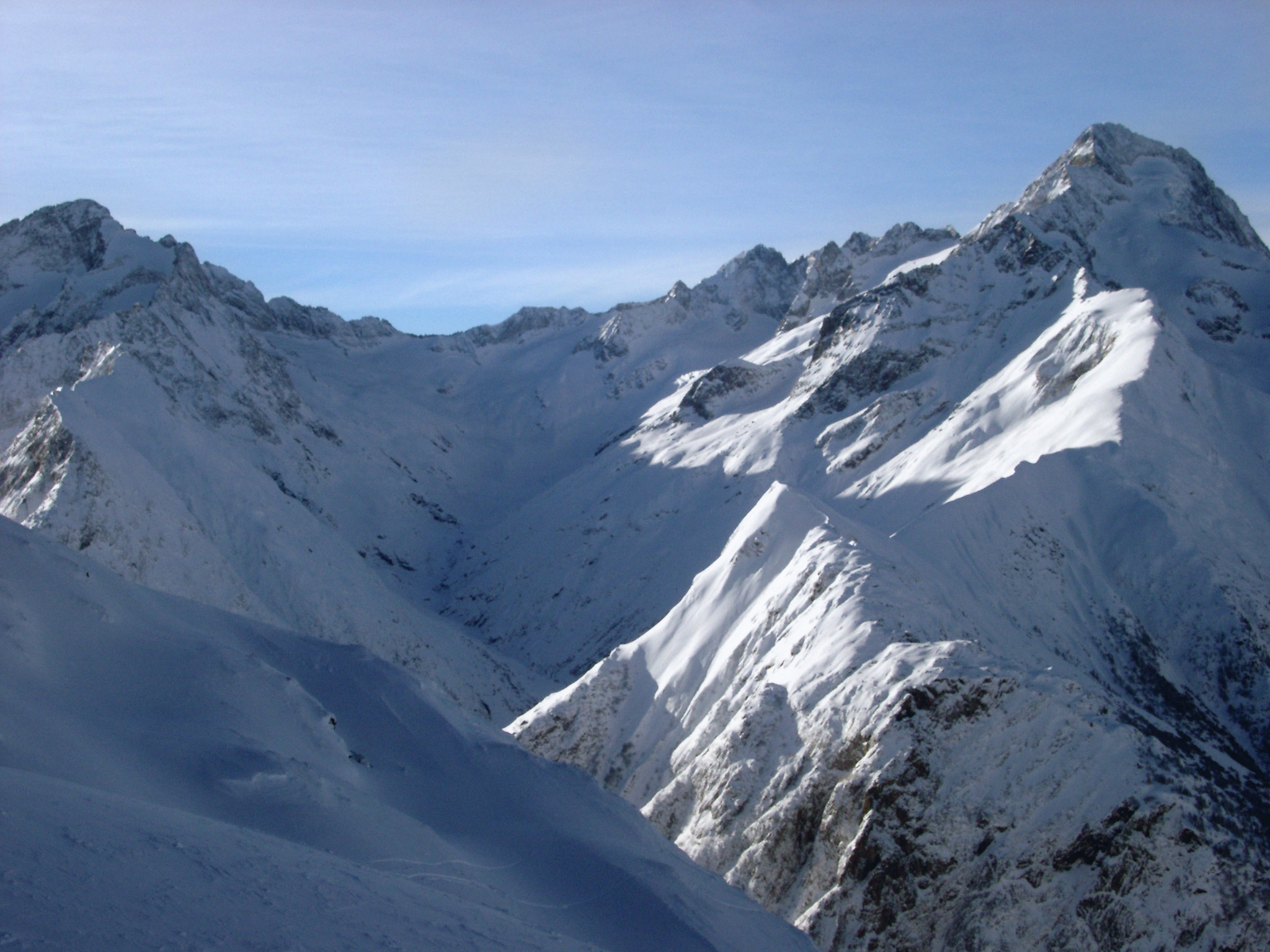 an image of Rugged peaks and steep valleys covered in deep white winter snow under a sunny clear blue sky in France during the holiday season