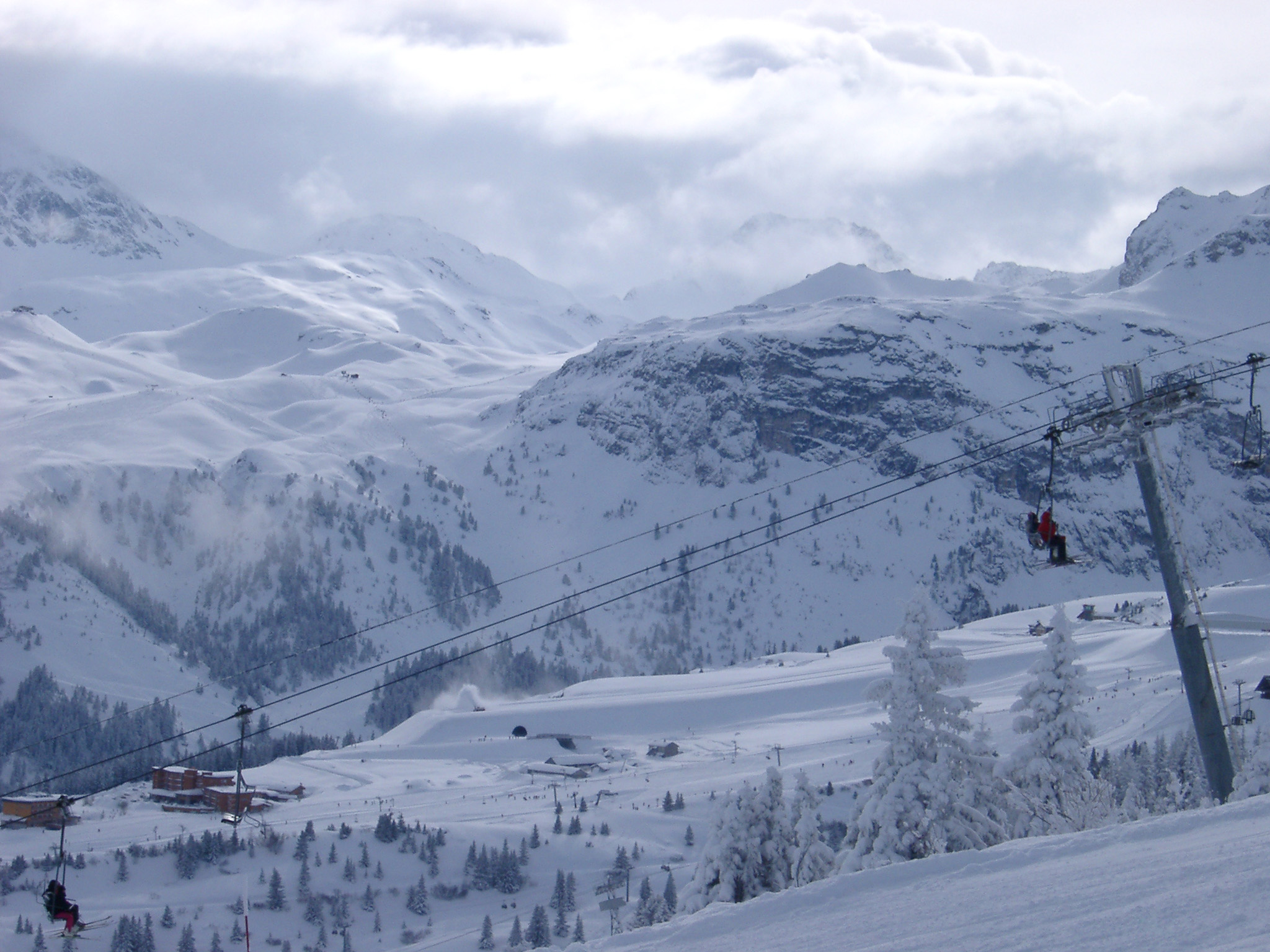 an image of Extensive View of Beautiful Piste for Mountain Sports, like Skiing and Snowboarding, Captured with Cable Cars Passing on Winter Holiday Season.