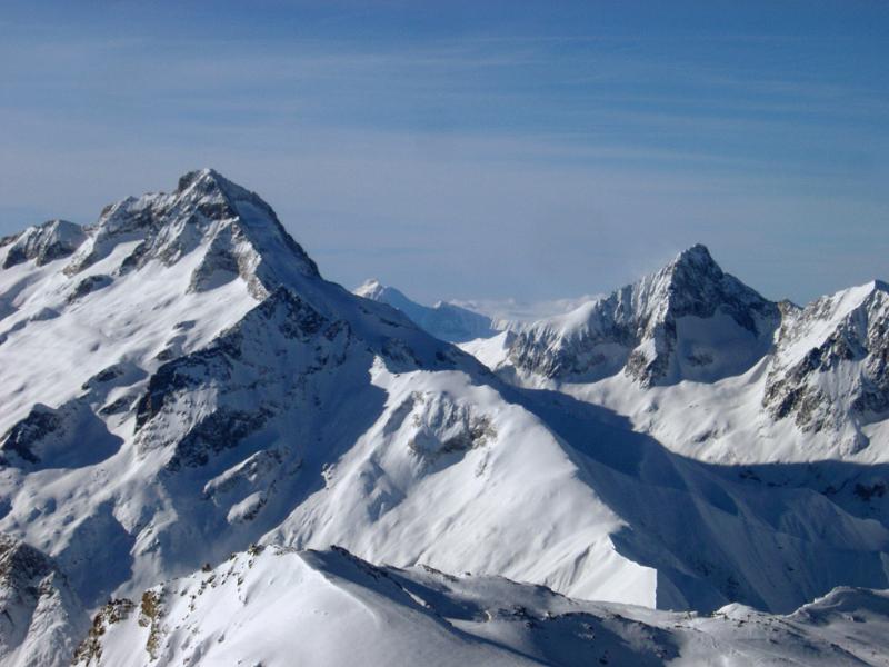 Winter snow on rugged alpine peaks during the holiday and skiing season under a clear crisp blue sky