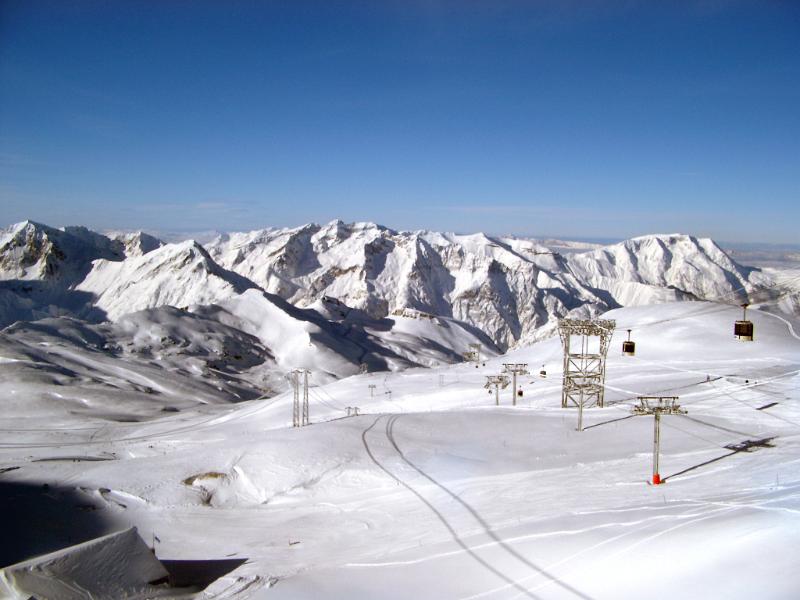 Scenic winter landscape with snow covered mountains and a piste with chair lifts for skiers