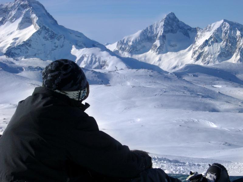Young snowboarder enjoying a day on the snow during a winter vacation to the Alps with snow covered peaks in the background