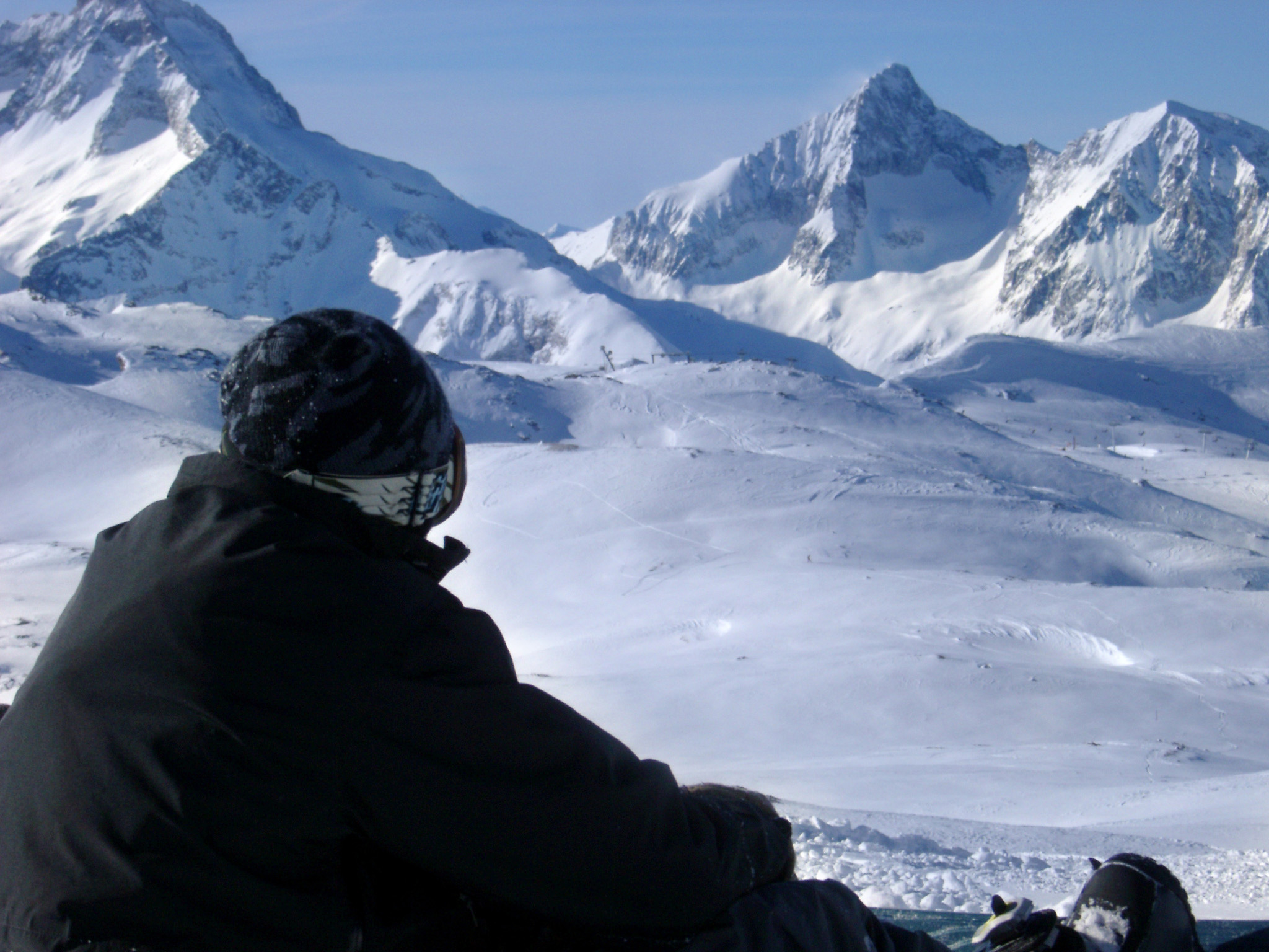 an image of Young snowboarder enjoying a day on the snow during a winter vacation to the Alps with snow covered peaks in the background