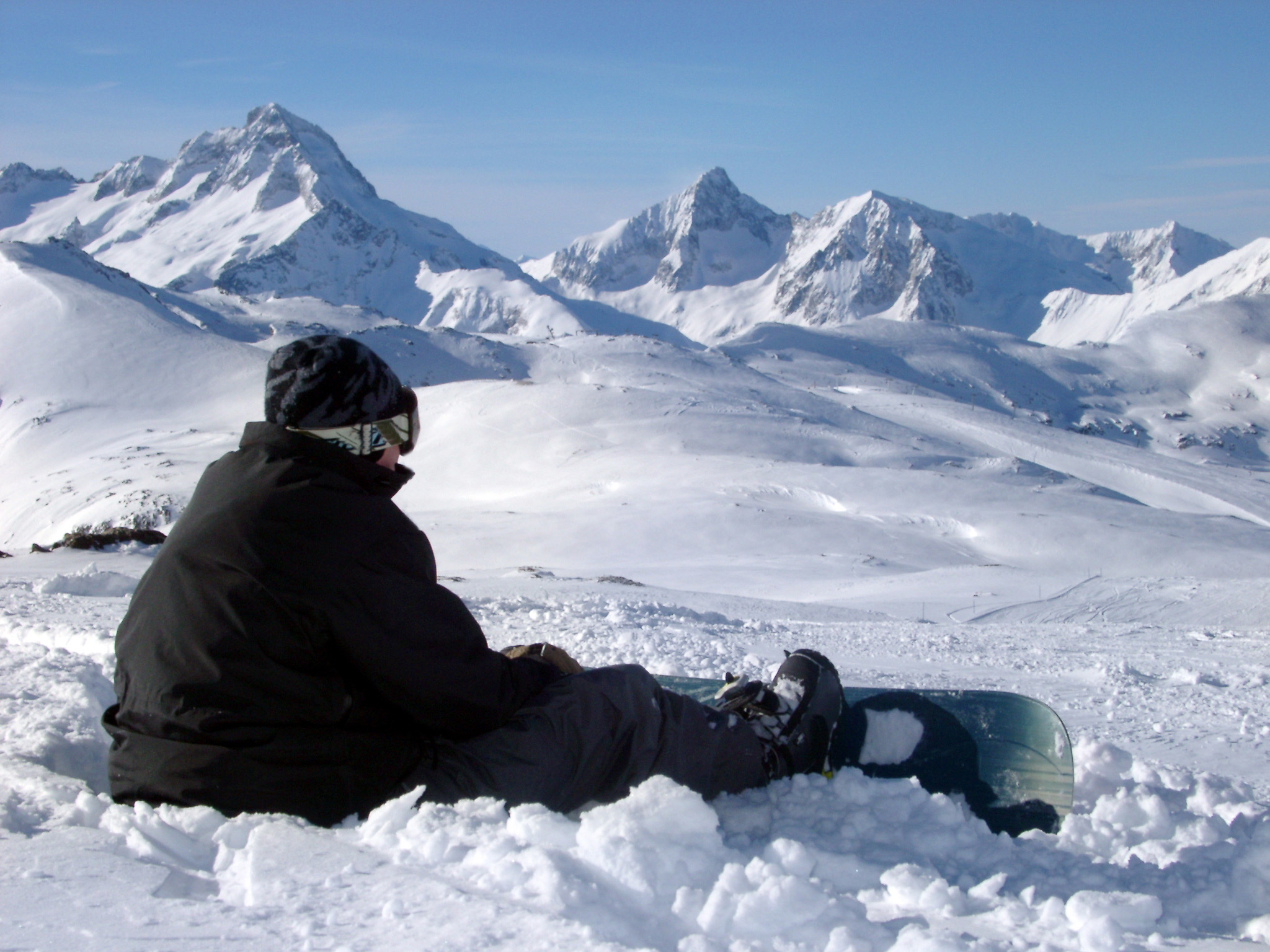 an image of Snowboarder in Black Jacket Relaxing During Winter Holiday Season.