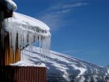 Winter holiday cabin in the Alps with a row of icicles hanging from the roof on a sunny blue sky winter day