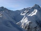 Rugged peaks and steep valleys covered in deep white winter snow under a sunny clear blue sky in France during the holiday season